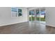 Open living room with wood tile flooring, large windows, and sliding glass doors to a patio at 1647 Sugarbelle Cir, Mascotte, FL 34753