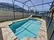 Inviting screened-in pool with spa, brick trim, and lounge chair offers a relaxing outdoor retreat at 1612 Herrons Green Path, Kissimmee, FL 34747