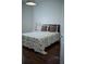 Neutral bedroom with wooden floors, queen bed, floral quilt, and accent pillows at 14421 Hatchee Ct, Orlando, FL 32837
