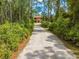 Long gravel driveway leads to a brick home surrounded by lush greenery and mature trees at 1775 Sundance Dr, St Cloud, FL 34771