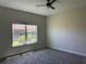 This bedroom has a ceiling fan and a window view with a green lawn at 1077 Quaker Ridge Ln, Davenport, FL 33896