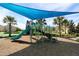 Outdoor playground with a slide and climbing structure, shaded by a blue canopy, in a Gathering-friendly community at 1077 Quaker Ridge Ln, Davenport, FL 33896