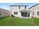 Home's well-maintained backyard has lush green grass, a covered patio, and young trees at 199 Bull Frog Ln, Umatilla, FL 32784
