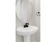 Close-up of a modern pedestal sink with black faucet and oval mirror in a bathroom at 199 Bull Frog Ln, Umatilla, FL 32784