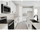 Bright, modern kitchen featuring white cabinets, gray countertops, and stainless steel appliances at 199 Bull Frog Ln, Umatilla, FL 32784
