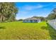View of a light blue single-story home with a large green backyard and a white fence at 319 Water Shore Dr, Leesburg, FL 34748
