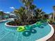 Community lazy river with palm trees, lush landscaping, and plenty of green inflatable floats for residents to enjoy at 2290 Lelani Cir, Davenport, FL 33897