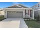 Attractive home showcasing a two-car garage, red shutter, and landscaped yard at 207 Bull Frog Ln, Umatilla, FL 32784