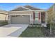 Charming home featuring stone accents, a two-car garage, and a well-manicured lawn at 207 Bull Frog Ln, Umatilla, FL 32784
