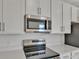 Close-up of kitchen featuring stainless steel microwave, range, and white cabinets at 207 Bull Frog Ln, Umatilla, FL 32784