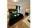 Chic main bedroom featuring a green bed with patterned pillows, full length mirror, and minimalist decor at 1676 Moon Valley Dr, Davenport, FL 33896