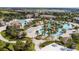 Aerial view of a community pool area with a lazy river, sand volleyball court, and beautifully landscaped grounds at 1676 Moon Valley Dr, Davenport, FL 33896