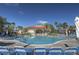 Community pool with lounge chairs and umbrellas with community building in the background at 121 Madiera Beach Blvd, Kissimmee, FL 34746