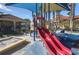 Community playground with a red slide and sand box, set against a backdrop of well-maintained buildings and mature trees at 121 Madiera Beach Blvd, Kissimmee, FL 34746