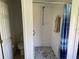 This bathroom has a shower with a grey tile floor, neutral colored walls, and a blue striped shower curtain at 1652 Dunes Ct, Haines City, FL 33844