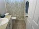 This bathroom has a vanity, toilet, and shower with a neutral colored walls and patterned shower curtain at 1652 Dunes Ct, Haines City, FL 33844
