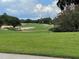 Expansive view of the golf course with bunkers, trees, and a cloudy sky at 1652 Dunes Ct, Haines City, FL 33844