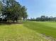 Scenic golf course view with lush green grass and mature trees under a clear sky at 1652 Dunes Ct, Haines City, FL 33844