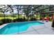 Screened-in pool with lounge chairs and views of the lush backyard and golf course at 1652 Dunes Ct, Haines City, FL 33844