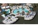 Aerial view of a sparkling community pool surrounded by palm trees, sun loungers, umbrellas, and a water feature at 2716 Bushman Dr, Kissimmee, FL 34746