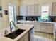 Bright kitchen with gray cabinetry and quartz counters with large island sink and bar at 319 Celebration Blvd, Celebration, FL 34747