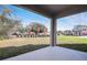 Covered patio overlooking a large, grassy backyard with mature trees and a view of the neighborhood at 535 Summit River Dr, Apopka, FL 32712