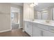 Well-lit bathroom with double vanity, white cabinets, modern fixtures, and a walk-in closet at 535 Summit River Dr, Apopka, FL 32712