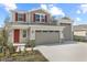 Charming two-story home with a two car garage, red shutters, landscaped yard, and a welcoming red front door at 2111 Riely Ave, Eagle Lake, FL 33839