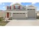Charming two-story home with a two car garage, red shutters, landscaped yard, and a welcoming red front door at 2111 Riely Ave, Eagle Lake, FL 33839