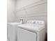 Modern laundry room featuring a white washer and dryer, with wire shelving above at 2111 Riely Ave, Eagle Lake, FL 33839
