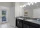 Bathroom featuring double vanity with granite countertop and door leading to outdoor patio space at 9099 Hazard St, Davenport, FL 33896
