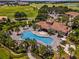 A lush aerial view of a resort-style community pool with a clubhouse, palm trees, and meticulously landscaped grounds at 9099 Hazard St, Davenport, FL 33896
