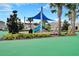 Community playground featuring a blue slide, covered play area, palm trees, and landscaping at 9099 Hazard St, Davenport, FL 33896