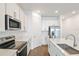 Well-lit kitchen featuring modern stainless steel appliances, white cabinetry, and a stylish central island at 2107 Riley Ave, Eagle Lake, FL 33839