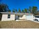Tan house with gray roof, white garage door, and landscaping at 6809 149Th Lane Rd, Ocala, FL 34473
