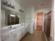 Bright bathroom featuring a double vanity with white cabinets and a view into the walk-in closet at 3960 Steer Beach Pl, Kissimmee, FL 34746