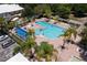 Aerial view of a large community pool with palm trees, sun loungers, and a covered area, perfect for recreation at 7127 Harmony Square S Dr # 7127, Harmony, FL 34773