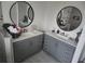 Modern bathroom with dual vanities and round mirrors, featuring sleek gray cabinets and stylish fixtures at 438 Spike Ct, Kissimmee, FL 34759