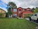 Two-story home with a well-manicured lawn and tropical landscaping, offering curb appeal and outdoor charm at 438 Spike Ct, Kissimmee, FL 34759