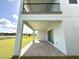 A covered patio shows a brick-paved area, supported by white pillars, overlooking a lake and lush green lawn at 13193 Tollcross Way, Winter Garden, FL 34787