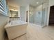 This bathroom is an oasis featuring a large tub, walk-in shower with marble surround, and modern fixtures at 13193 Tollcross Way, Winter Garden, FL 34787