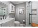 Bathroom featuring white vessel sink vanity, toilet, medicine cabinet, and glass-enclosed shower with marble-style tiling at 4321 Rummell Rd, St Cloud, FL 34769