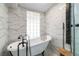 Bright bathroom featuring a freestanding tub, marble walls, and a shower with modern fixtures at 4321 Rummell Rd, St Cloud, FL 34769