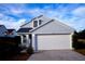 Two-story house with gray siding, white garage door, and landscaping at 523 Royal Ridge Dr, Davenport, FL 33837