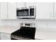 Close-up of stainless steel oven and microwave with white countertops and cabinets at 1753 Carnelian St, Deland, FL 32720