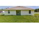 A lush green backyard with a view of the home's back exterior with double doors and windows at 1415 Orlando Way, Kissimmee, FL 34759