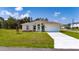 Inviting single-story home with manicured lawn, colorful flowerbeds, and attached two-car garage on a sunny day at 1415 Orlando Way, Kissimmee, FL 34759