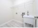 Bright laundry room with sink, connections, white walls, wire shelving, and wood flooring at 1415 Orlando Way, Kissimmee, FL 34759