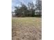 Empty lot with sparse grass and some trees in the background at 1415 Orlando Way, Kissimmee, FL 34759