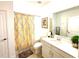 Well-lit bathroom with vanity, mirror, shower with yellow patterned curtain, and neutral color scheme at 1608 Cross Prairie Pkwy, Kissimmee, FL 34744